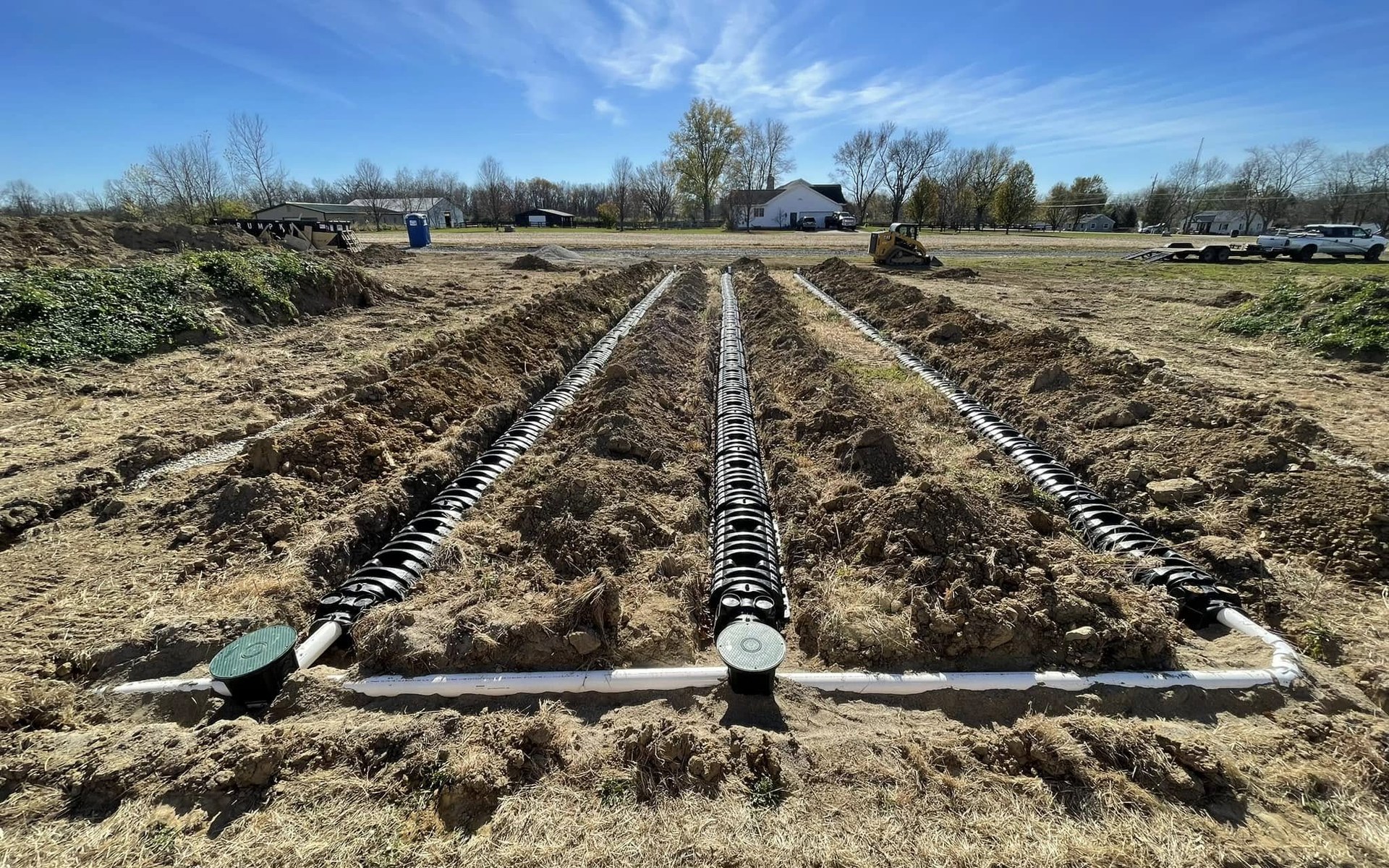 Residential septic drainfield lines installed in prepared soil under a clear sky